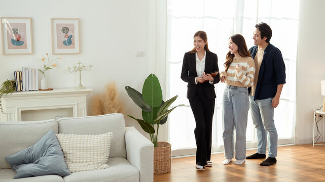 Real Estate Agent Showing a Modern Apartment to Young Couple During Daylight Hours in Bright Living Room