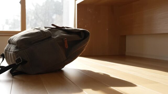 Backpack on floor near wooden desk in bright indoor setting  