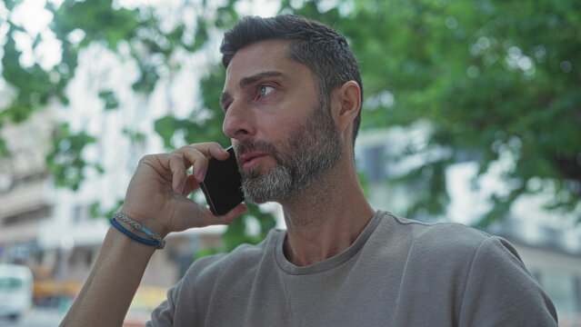 Man holding smartphone to ear on city street, speaking with animated expression and hand gesture; urgent business call concern.