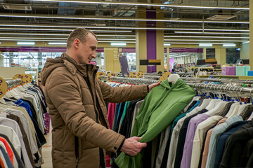 A man chooses casual clothing. Sweater. Textile industry. Clothing store