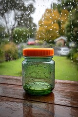 Rainy Day Still Life - Green Jar with Orange Lid on Wood.