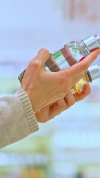 Vertical video: Woman reading the label of a cosmetic product in a store aisle, focusing on ingredients, with shelves and bottles in the background.