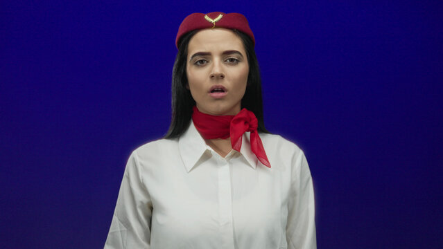 Flight attendant woman in uniform on a blue background appears frustrated and thoughtful, conveying emotion through facial expressions and gestures.