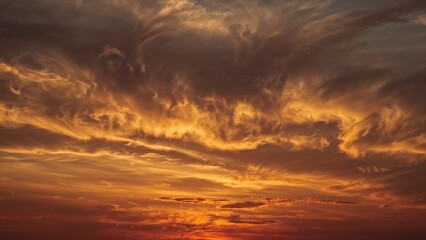 Sunset sky with dramatic clouds and vibrant orange and golden hues. Nature, landscape, sky. Atmospheric and scenic view of the sunset.