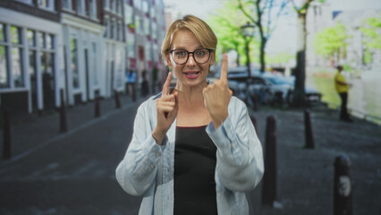 Woman showing five fingers and pointing with index finger on a city street while smiling and raising a fist; joy celebration.