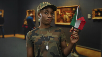 Woman soldier holding kuwait flag while wearing camouflage uniform and dogtag in gallery building;...