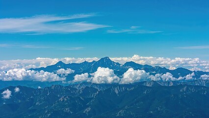 Naklejka premium Mountain range with clouds and blue sky, capturing the natural beauty of mountain landscapes.