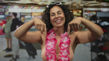 Hispanic woman with bare arms points index fingers downward in store; promotion discount invitation offer.