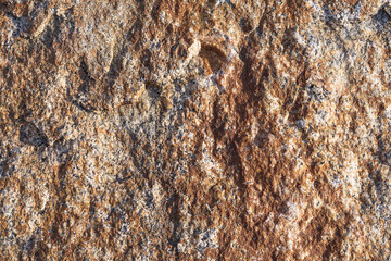 Natural rough stone texture with brown and gray tones in detailed closeup. Rocky mineral surface pattern suitable for backgrounds and design.