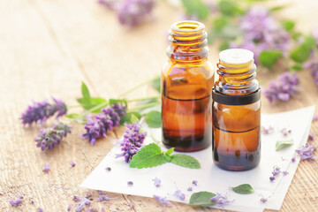 Patchouli essential oil or extract in glass bottle dropper with flowers on wooden table, closeup, natural medicine and healthy skin and body treatment concept