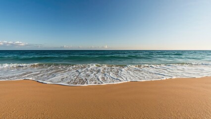 A peaceful sandy beach with gentle waves and a clear blue sky.