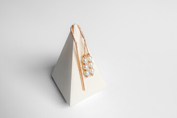 A pair of elegant threader earrings crafted from rose gold. Each earring  features a delicate, long chain that threads through the ear with three small pearls.