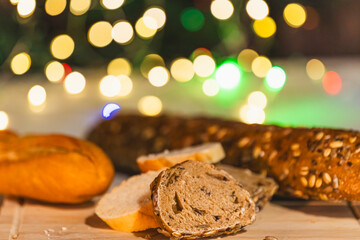 Black and white loaves of bread with grains on wooden board, sliced pieces