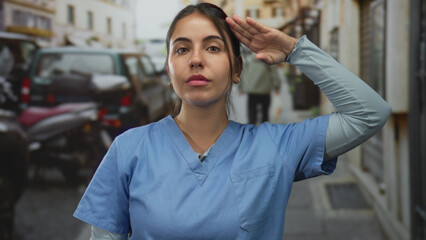 Young hispanic nurse salutes with hand raised on a busy city street at sunrise; patriotism honor duty pride.