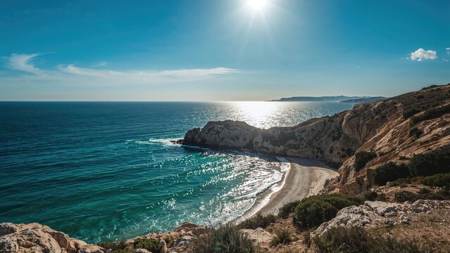 Coastal landscape with cliffs and beach under bright sun and clear sky. Seaside scenery, ocean, nature, and coastline. The image captures a serene coastal environment.