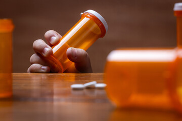 A powerful conceptual photograph showing a child's hand reaching for colorful, unattended prescription pills or medication.