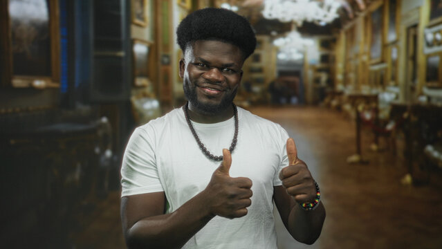 Man showing open palms and smiling face, presenting empty hands toward viewer inside museum building lined with framed paintings and velvet ropes; confidence.