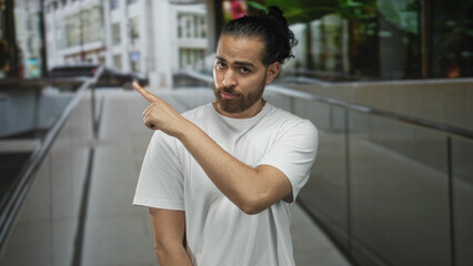 Man points finger on urban street beside glass building, visible hand gesture and facial...