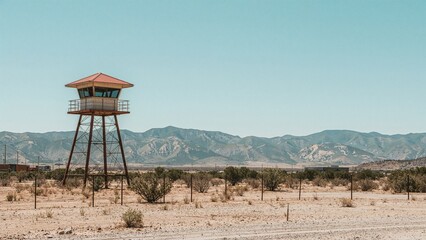 A watchtower in a desert landscape with mountains in the background