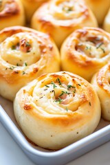 Freshly baked savory rolls filled with cheese and herbs, golden brown crust, arranged in a white baking dish, perfect for appetizers or snacks with copy space