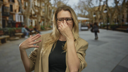 Fototapeta premium Woman pinching nose because of bad smell at street surrounded by urban scenery blending discomfort with curiosity.