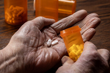 A detailed close-up shot of wrinkled, elderly senior hands carefully dosing pills from a prescription bottle.