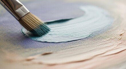 Close-up of paintbrush spreading thick teal paint onto a textured canvas, symbolizing creativity and artistic process.