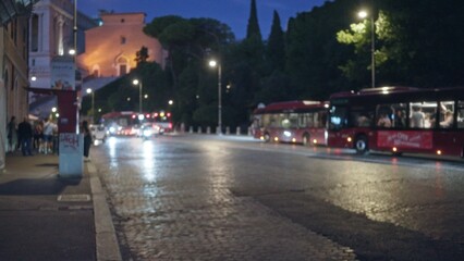 Blurred bokeh street scene in rome at dusk with soft defocused lights, cobblestone pavement and distant illuminated facades; backplate template copyspace calm.