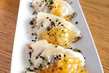 Steamed dumplings served on plate with sesame seeds