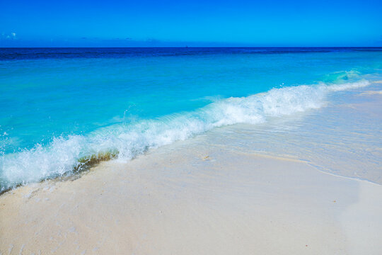 Beautiful view of Caribbean Sea waves at Eagle Beach washing sandy shore background blue sky. Aruba.