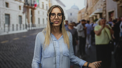 Fototapeta premium Woman talking into headset on a busy street near historic building, wearing glasses and blue shirt; customer service confidence.