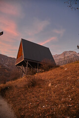 A-frame cabins on snowy hillside at sunrise, under construction, forest retreat with mountain view.