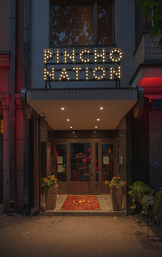 Helsinki, Finland - August 06 2025: Restaurant entrance with illuminated Pincho Nation sign at night.
