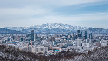Obraz premium City skyline with snow-capped mountains in the background. Urban landscape with tall buildings. Winter city view with mountain range.