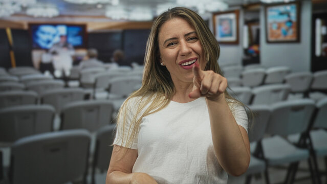 Woman pointing finger toward camera and giving thumbs up at gallery building; encouragement motivation positivity support.