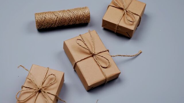 Gift boxes tied with twine and a twine roll, arranged on a cool grey background