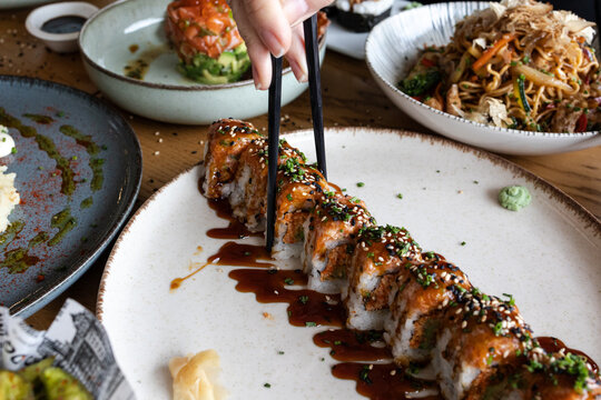Hand picking sushi roll with chopsticks at restaurant