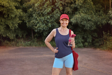 Fototapeta premium mulher de 50 anos feliz durante prática de exercícios físicos ao ar livre