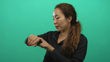 Woman pointing at wrist and checking the time in studio green screen; anticipation time awareness now.