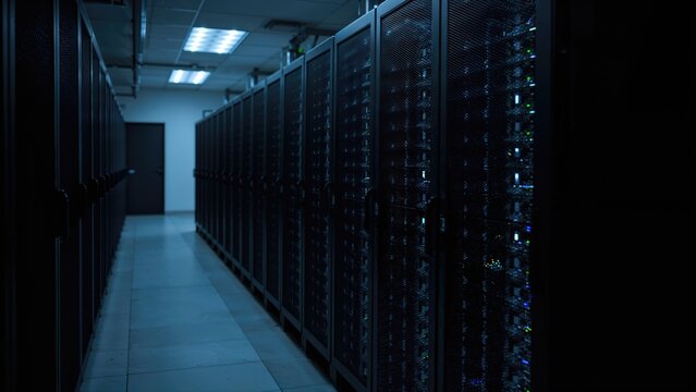 A data center with server racks in a dark room. Technology and data storage, concept. Server and network infrastructure. The concept of data management and information technology