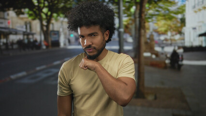 Man making neck-cutting gesture on city street with trees and buildings in the background, conveying an intense emotion.