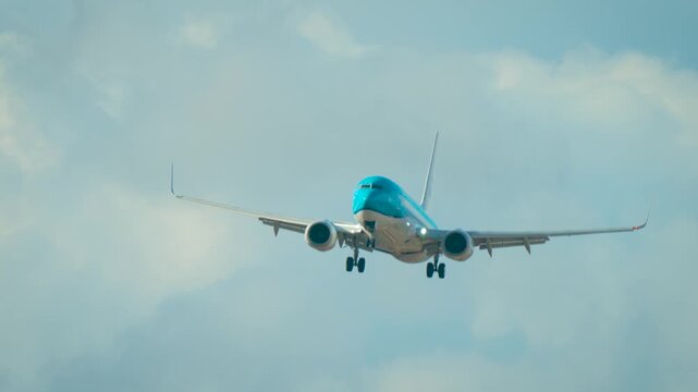 Airliner battling strong crosswind while flying in cloudy sky. Passenger jet facing wind gusts with slight tilt visible. Aircraft descending under daylight conditions with gear extended. Twin engine