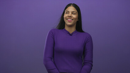 Fototapeta premium Latin woman with long straight hair wearing purple sweater smiling with tilted head in studio; happiness confidence optimism.