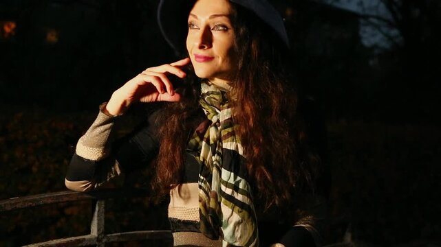 Elegant bright makeup smiling woman in blue retro hat sitting on the bench in vintage fashion dress outdoor autumn, empty copy space. Closeup face head portrait. Red lipstick, long brown hair