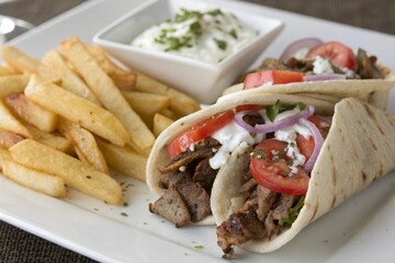 two greek gyros with shaved lamb and french fries 2