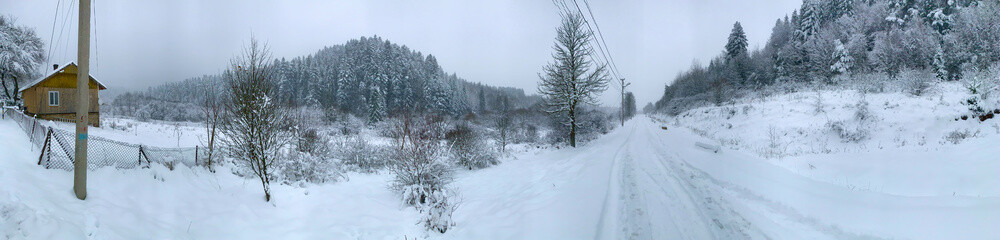 Snowy mountain landscape with a small house and a road in winter. 