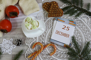 December 25th Calendar: The number 25 and the month's name in English on a decorative calendar surrounded by a lace napkin and Christmas sweets