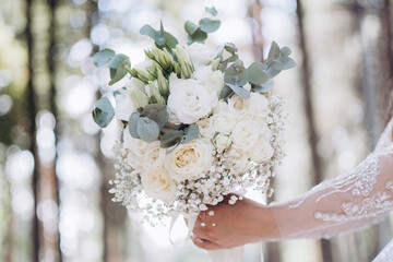 A close-up shot of the bride’s hand gently holding her floral bouquet, highlighting the delicate...