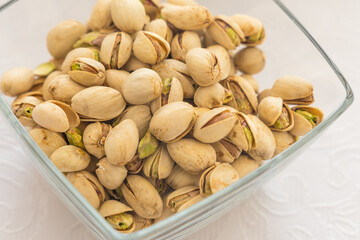 A detailed close-up shot from above of a glass bowl brimming with in-shell pistachios