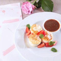 Cheesecakes with strawberries and jam. Healthy breakfast in the cafe. A menu page and a rose on the table. View from above.